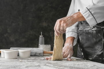 Man kneading dough on black background
