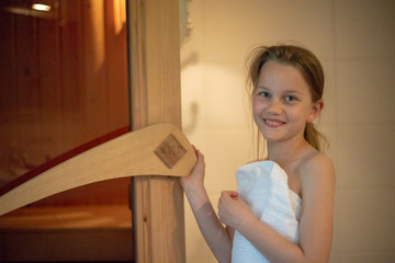Ein Mädchen öffnet lächelnd die Tür der finnischen Sauna