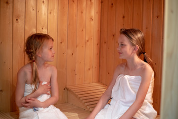 2 Mädchen sitzen in der Sauna und schauen sich an