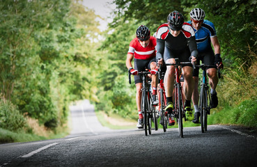 Cyclists racing on country roads on a sunny day in the UK. - obrazy, fototapety, plakaty