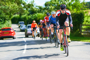 Cyclists racing on country roads on a sunny day in the UK.