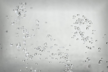 Abstract background, drops of water splash in the air on a light background. Splashes of water jets of water from a fountain close up. Interesting beautiful form