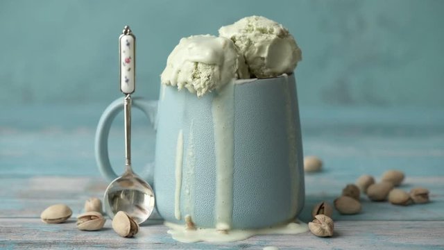 Cinemagraph - Pistachio ice cream in cup on wooden table.  Drops of ice cream dripping . Motion Photo.