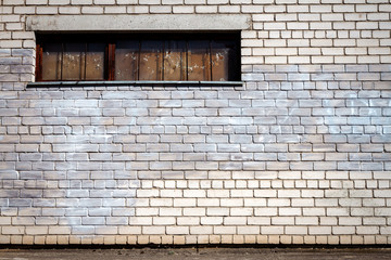 White brick wall with a boarded window