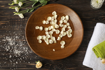 Beautiful spa composition with plate of water and flower petals in salon