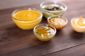 Bowls with different sauces on wooden background