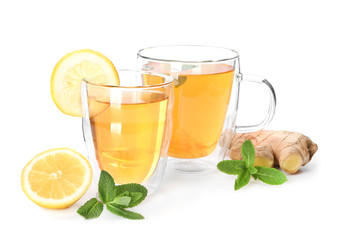 Cups of delicious tea with ginger and lemon on white background