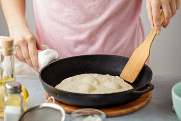 Woman frying mexican flatbread on cast iron pan.