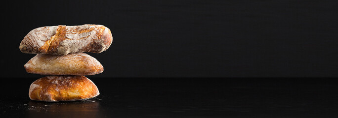 a pile of fresh Italian bread on black background