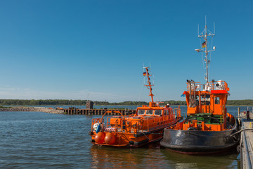 Zwei orange Boote liegen am Hafen 