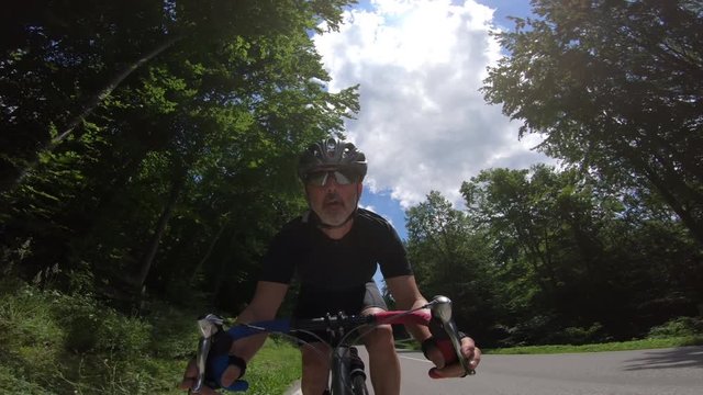 4K video face view of race cycler cycling down street
