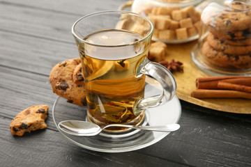 Cup of hot aromatic tea with cookies on wooden table