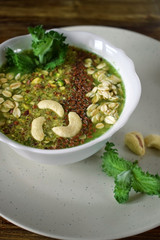 Green smoothie bowl topped with nuts, flax seeds and oatmeal flakes