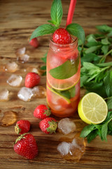 Lemonade with strawberry, lime, ice cubes and mint in a glass bottle