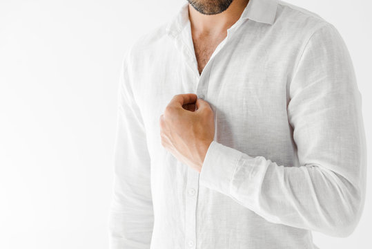 cropped image of male model unbuttoning linen white shirt isolated on grey background
