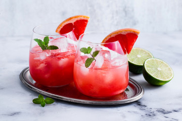 alcoholic cocktail Paloma of grapefruit and ice in glasses on a marble table . refreshing drink with lime juice