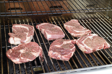 Ribeye steaks on a barbecue ready for cooking.
