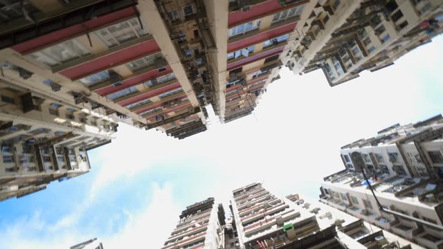 Low angle view of crowded residential towers in an old community in Hong Kong. Scenery of overcrowded narrow apartments, a phenomenon of high housing density. Rotating camera.