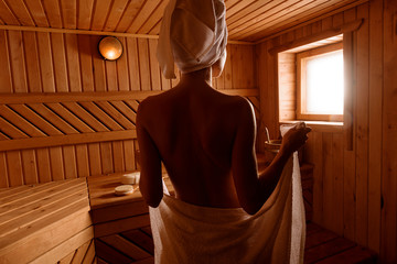 girl in a spa treatment in a traditional sauna with a brush for skin and a washcloth. relaxes...