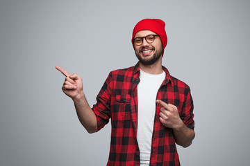 Cheerful man pointing away on gray