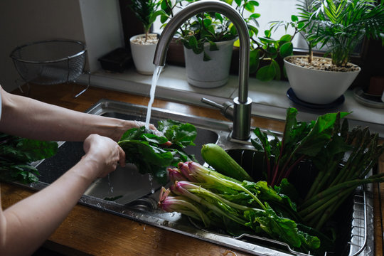 Fototapeta Woman washing fresh vegetables in kitchen