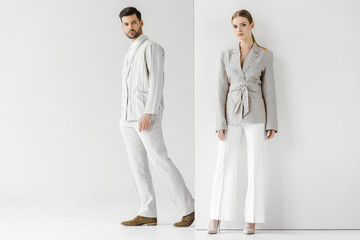 young male and female models in vintage clothes looking at camera on white