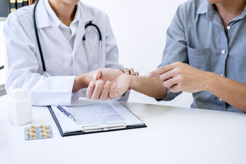 Doctor in white coat taking and checking the Patient's wrist pain during the examination