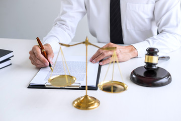 Businessman or lawyer working on a documents, judge gavel with Justice lawyers at law firm in background, Legal law, advice and justice concept