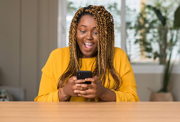 African american woman using smartphone scared in shock with a surprise face, afraid and excited...