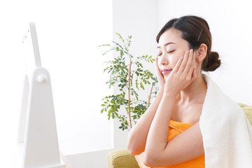 部屋でスキンケアをする若い女性