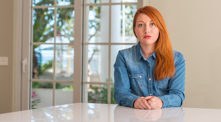 Redhead woman at home with a confident expression on smart face thinking serious