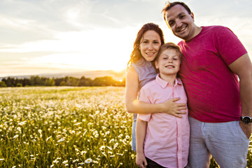 Happy family having fun on daisy field at sunset