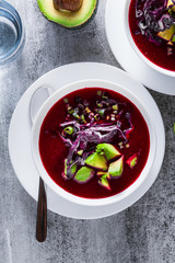 Beetroot gazpacho soup with blue cabbage, avocado and green onions with lime juice on the table . healthy summer vegan food