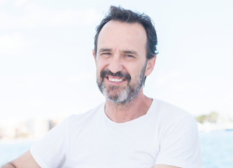 Handsome senior man traveling on sailboat and smiling happy and confident