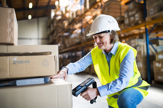 Senior warehouse woman worker working with barcode scanner.