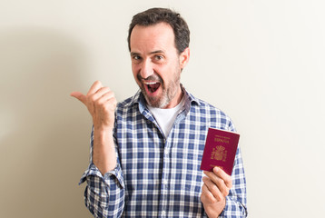 Senior man holding spanish passport pointing with hand and finger up with happy face smiling