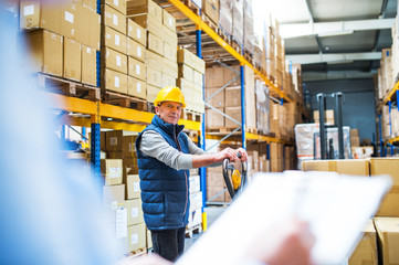 Senior woman manager and man worker working in a warehouse.