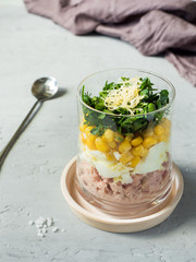 Fresh tuna salad with egg corn greens in a glass Cup on a concrete table. copy space