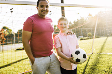 Naklejka premium man with child playing football outside on field