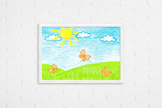 Frame mock up on white bricks wall with colored pencils drawing, author's design illustration. Blue sky, orange butterflies in the field. Wall art decor 