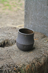 A simple clay cup rests upon a tree stump