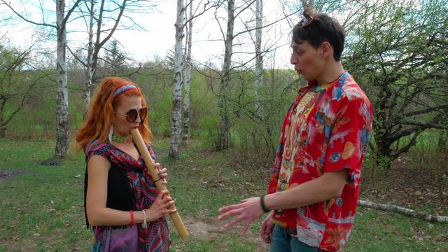 Red hair hippie girl learns to play on native musician instrument with her smiling friend