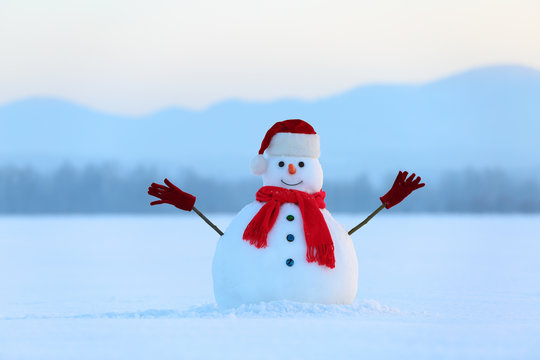 Winter scenery. Christmas snowman wearing red hat, scarf and gloves. High mountains. Nice fairy snowy day.