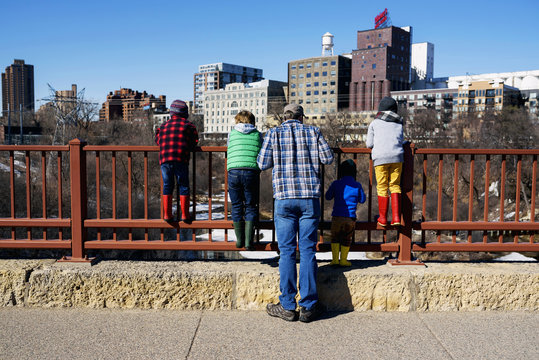 Father standing on Stone Arch bridge looking at cityscape with his four children, Minneapolis, Minnesota, America, USA