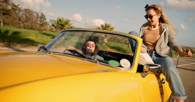 Hipster woman entering convertible car for road trip with friend