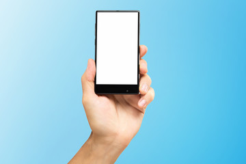Mockup of male hand holding frameless cell phone with blank screen isolated at blue background.