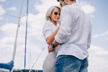 low angle view of beautiful stylish young couple in sunglasses hugging on yacht