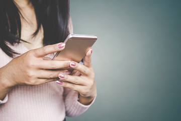 business woman hand using smart phone standing over grey wall background with copy space  