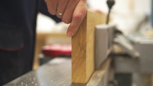 Male hand working with wooden plank using industrial carpentry equipment