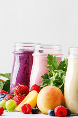 Healthy and useful colorful berry smoothies with yogurt, fresh fruit and berries on a gray background, selective focus